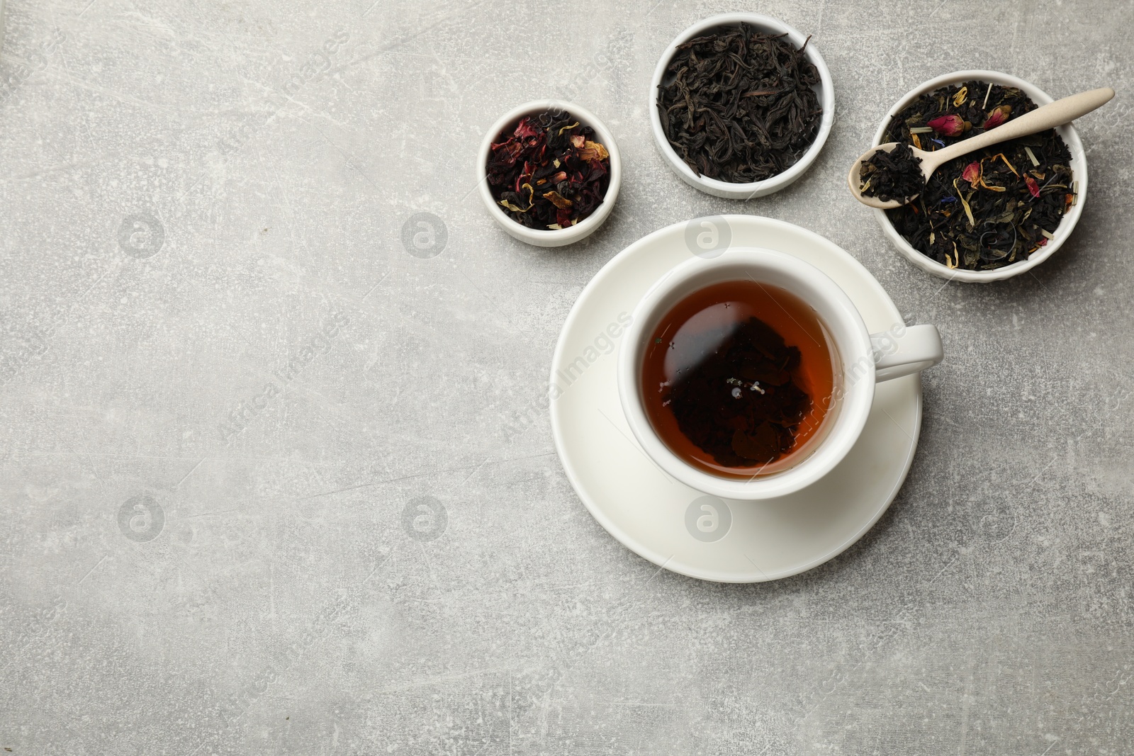 Photo of Aromatic tea and dried leaves on grey table, flat lay. Space for text