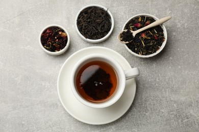 Photo of Aromatic tea and dried leaves on grey table, flat lay