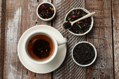 Photo of Aromatic tea and dried leaves on wooden table, flat lay