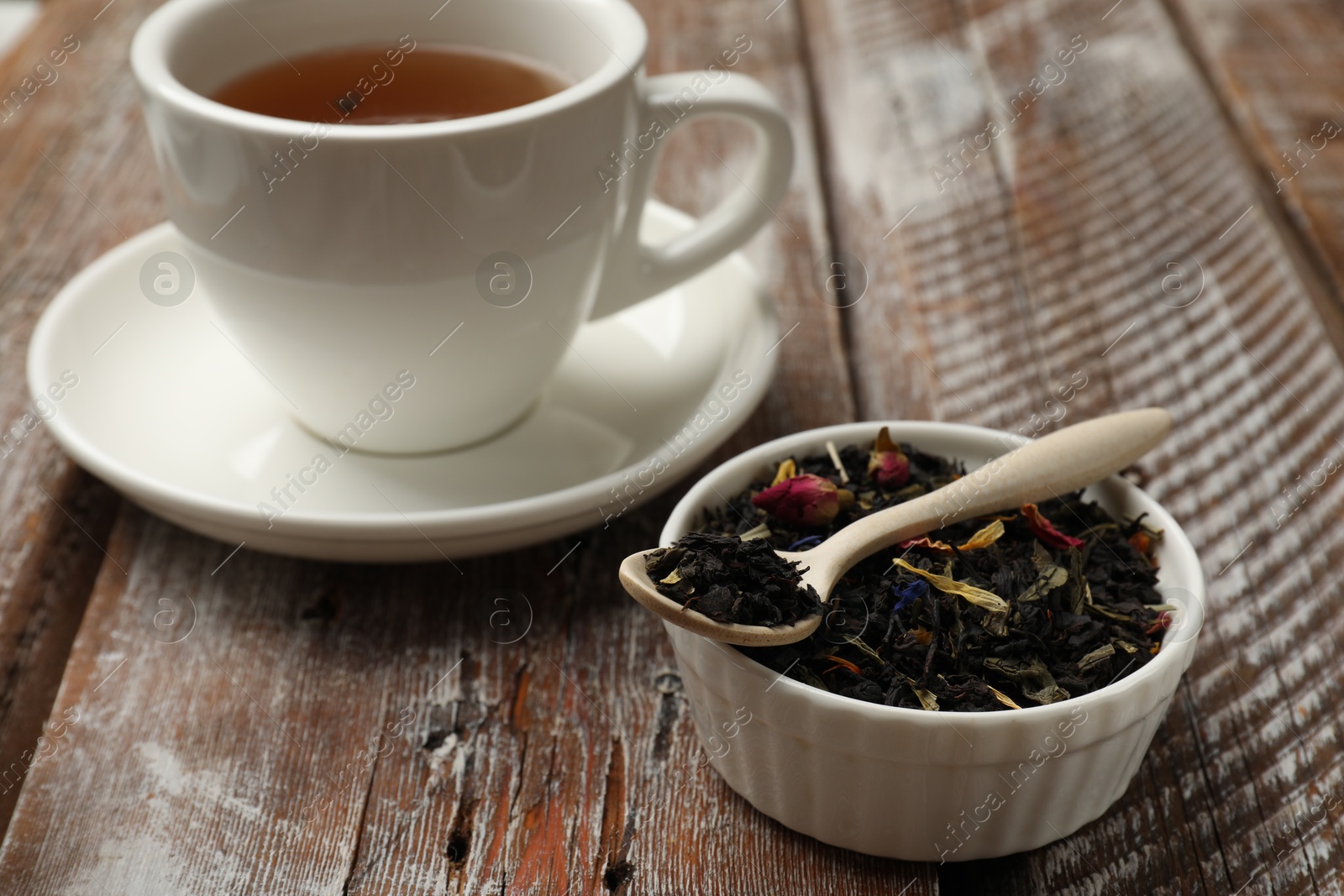 Photo of Aromatic tea and dried leaves on wooden table, closeup