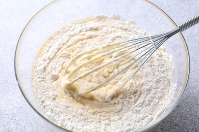 Photo of Whisk and bowl of dough on grey table, above view