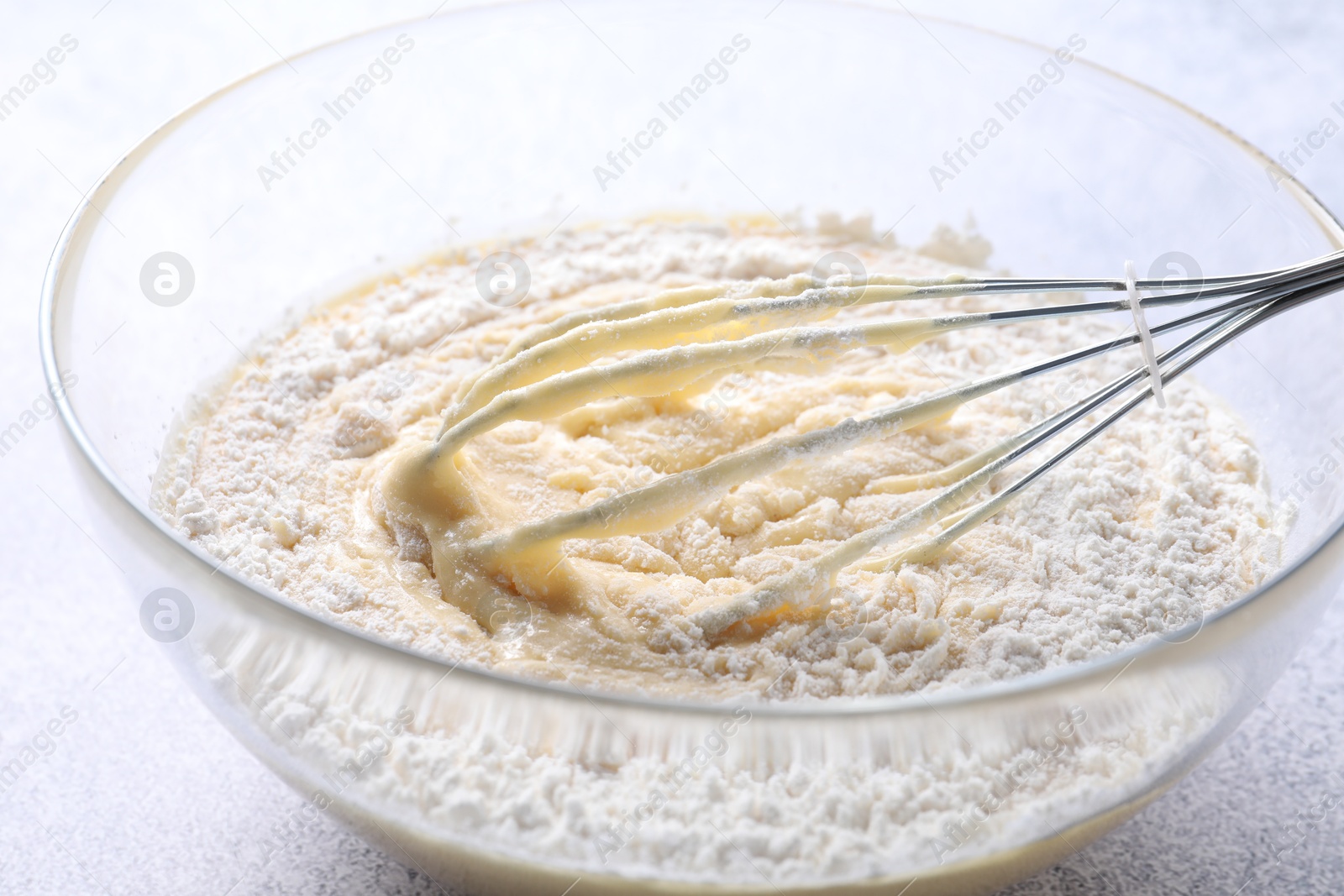 Photo of Whisk and bowl of dough on table, closeup