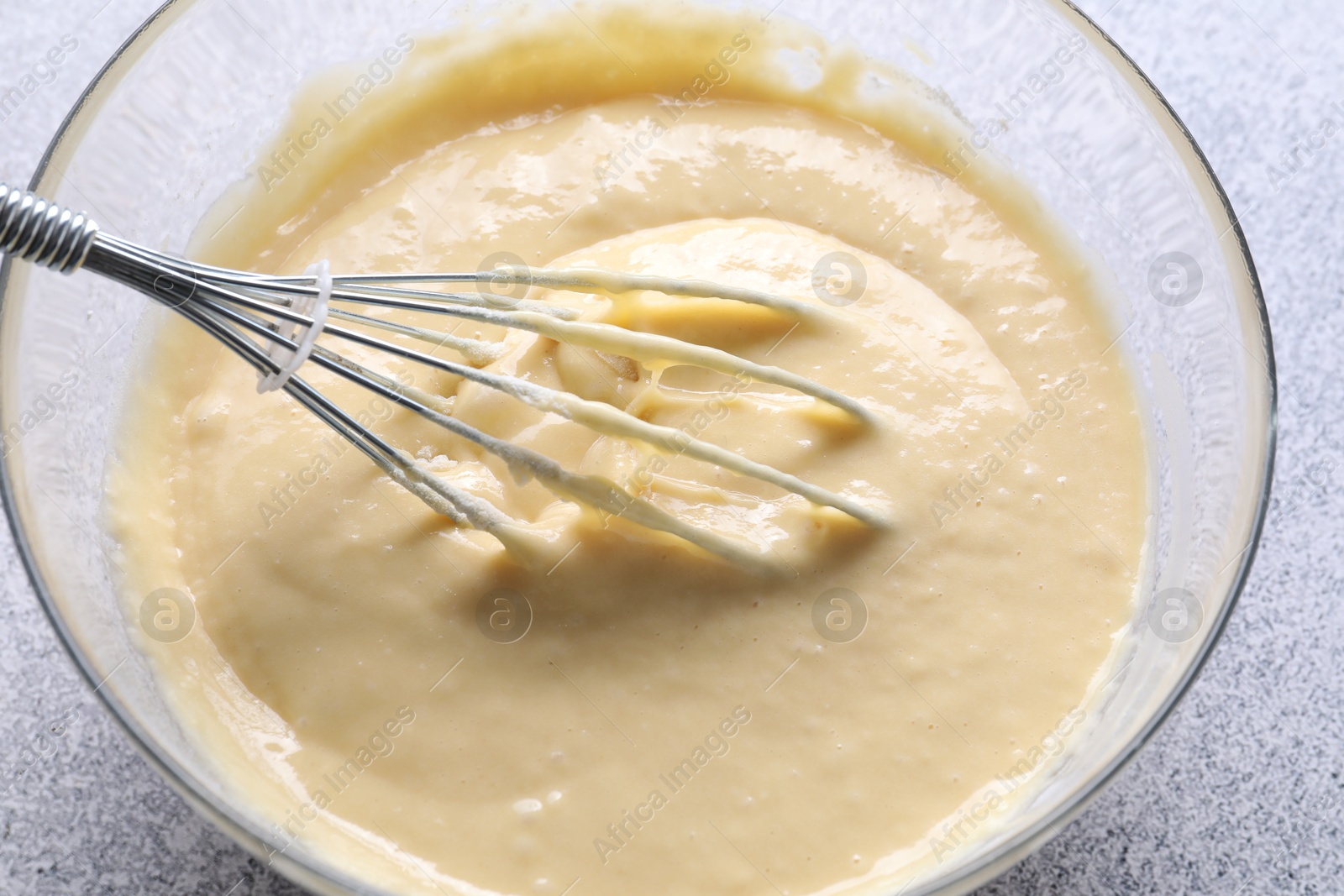 Photo of Whisk and bowl of dough on grey table, above view