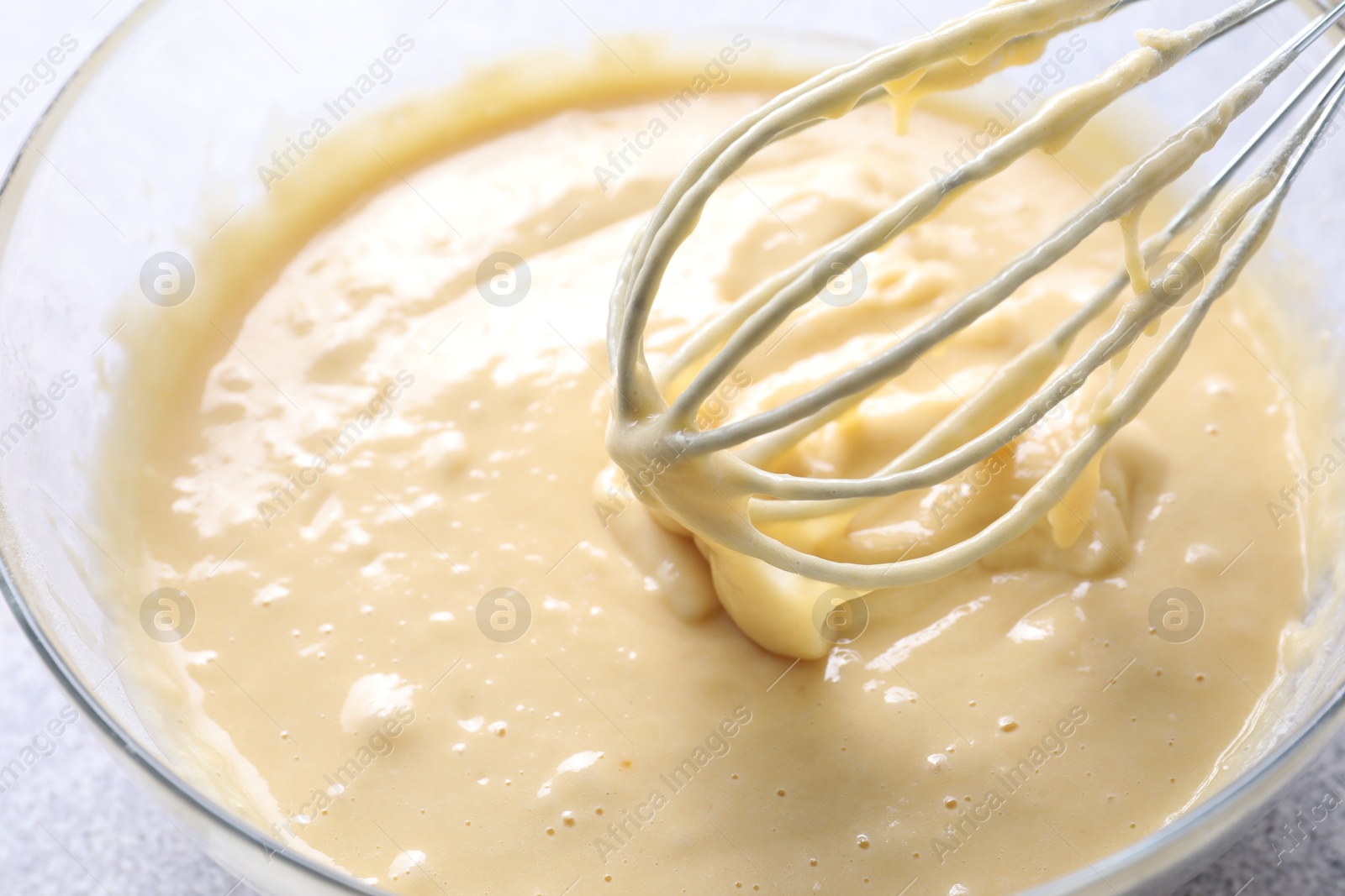 Photo of Whisk and bowl of dough on table, closeup