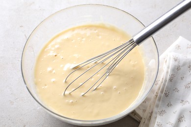 Photo of Whisk and bowl of dough on grey table, above view