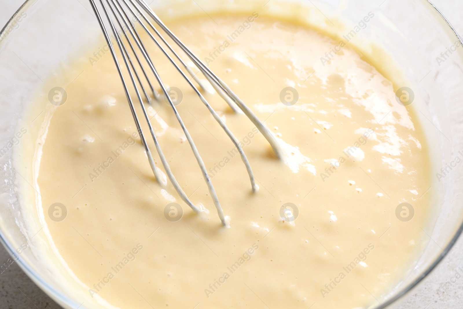 Photo of Whisk and bowl of dough on table, closeup