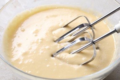 Photo of Making dough in bowl with hand mixer, closeup