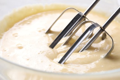 Photo of Making dough in bowl with hand mixer, closeup