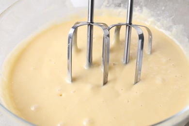 Photo of Making dough in bowl with hand mixer, closeup