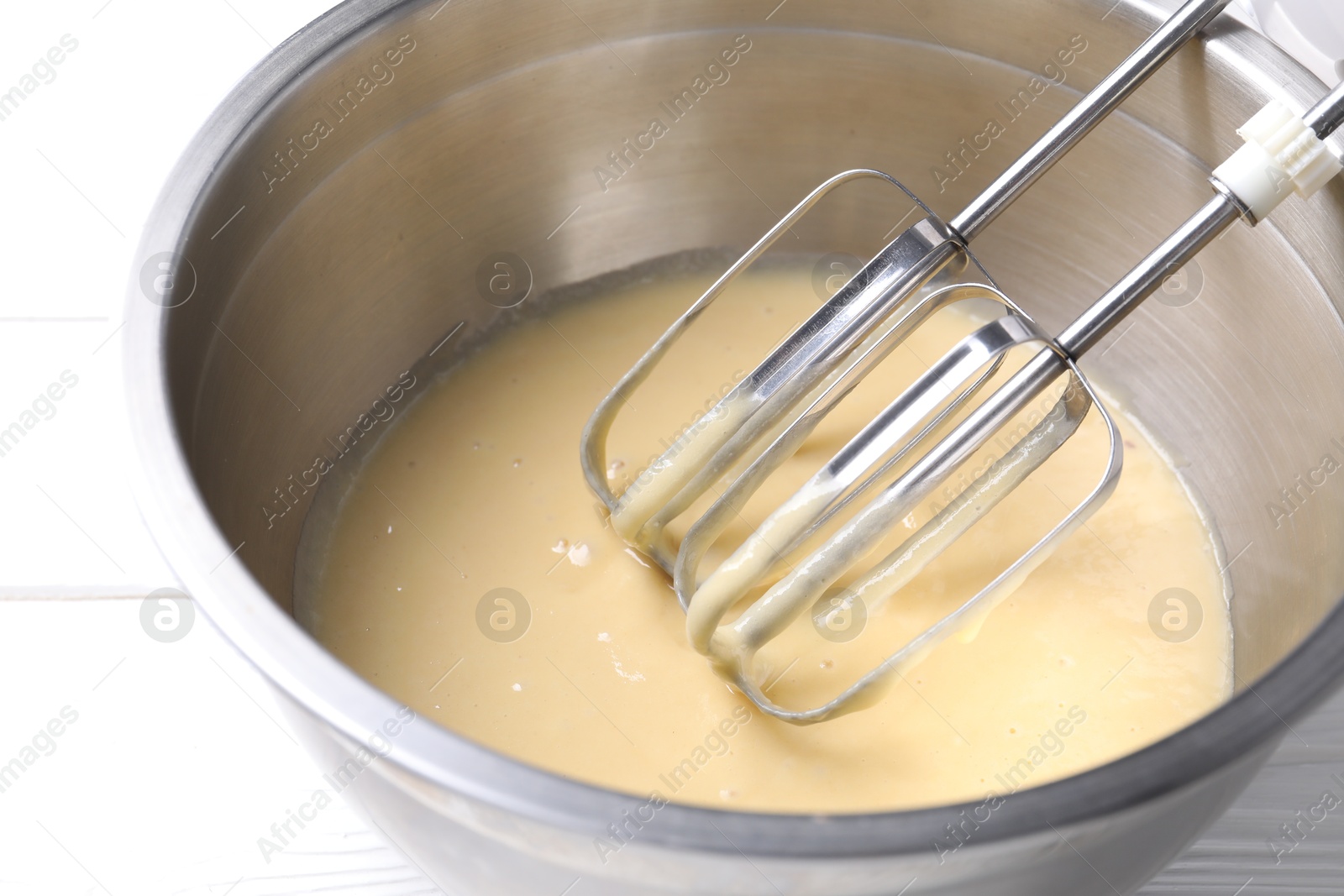 Photo of Making dough in bowl with stand mixer at white table, closeup