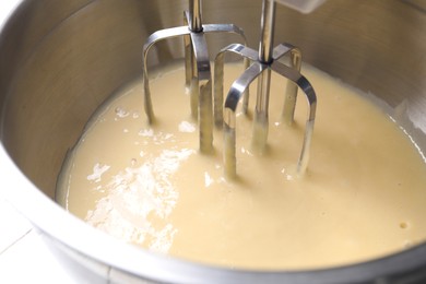 Photo of Making dough in bowl with hand mixer, closeup