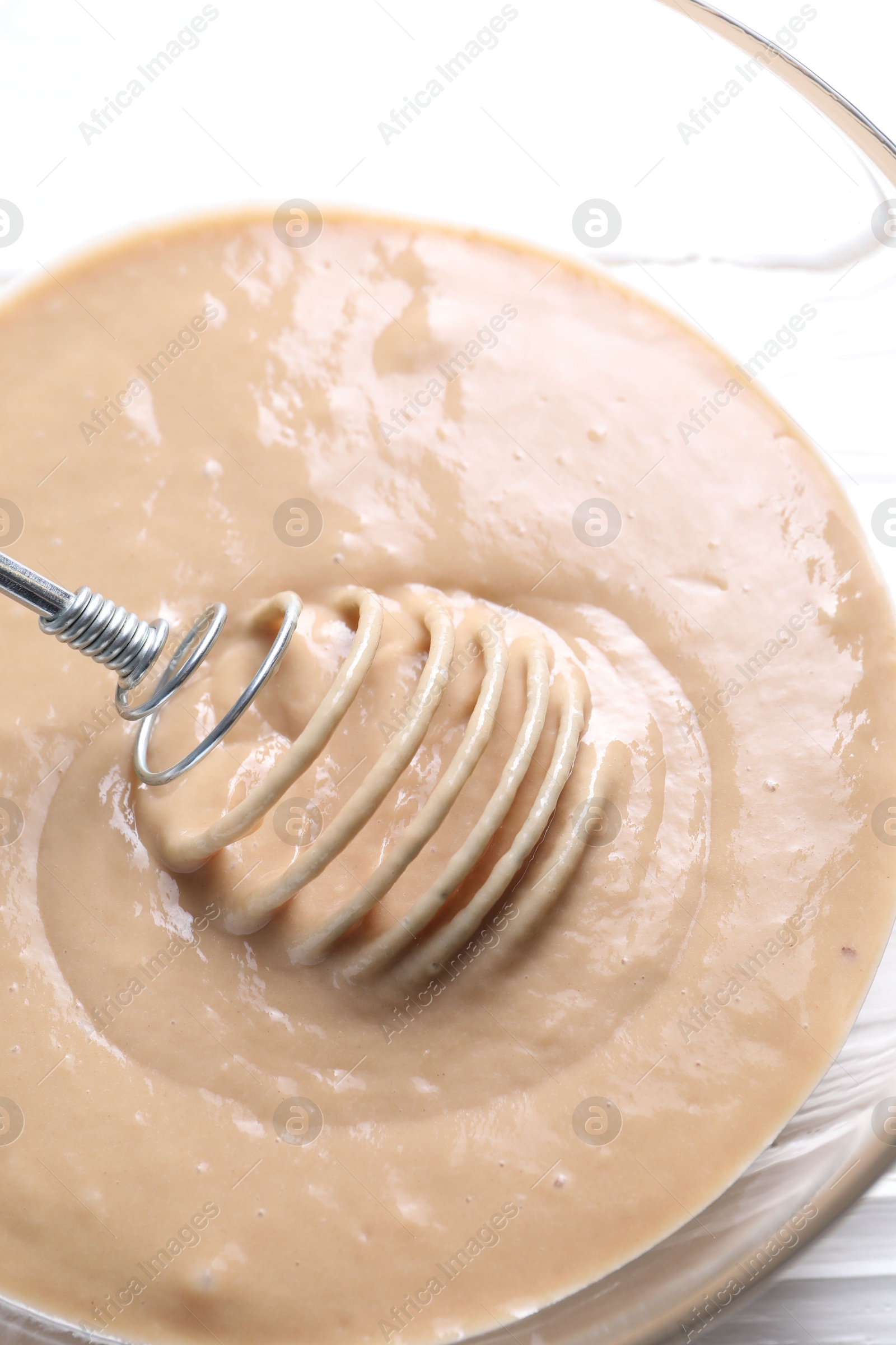 Photo of Whisk and bowl of dough on table, above view