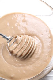 Photo of Whisk and bowl of dough on table, above view