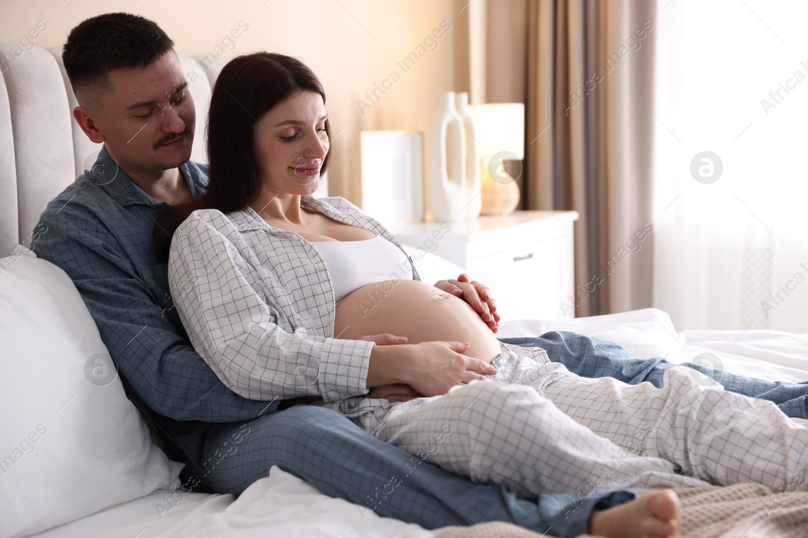 Photo of Pregnant woman and her husband on bed at home