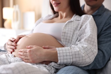 Photo of Pregnant woman and her husband on bed at home, closeup