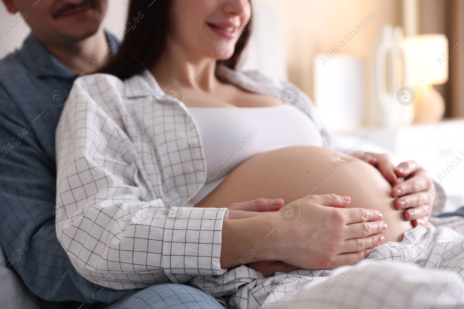 Photo of Pregnant woman and her husband on bed at home, closeup