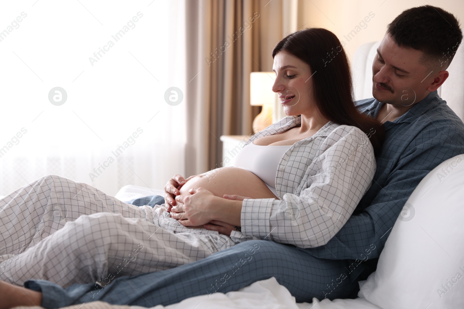 Photo of Pregnant woman and her husband on bed at home