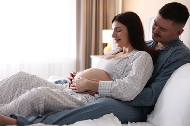 Pregnant woman and her husband on bed at home