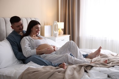 Photo of Pregnant woman and her husband on bed at home