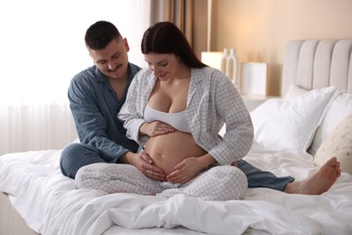 Photo of Pregnant woman and her husband on bed at home