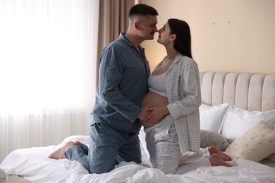 Photo of Pregnant woman and her husband on bed at home