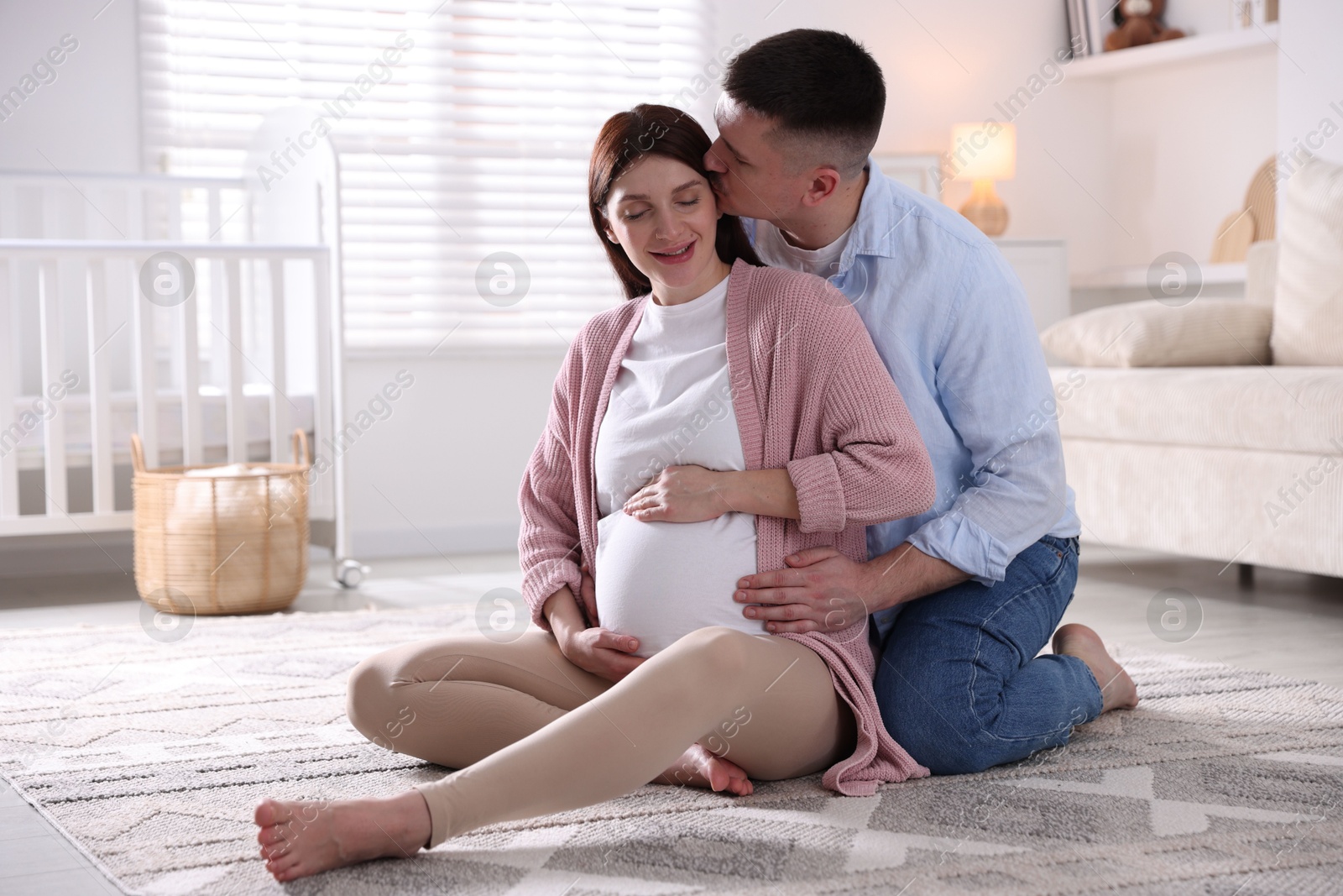 Photo of Pregnant woman and her husband on floor at home