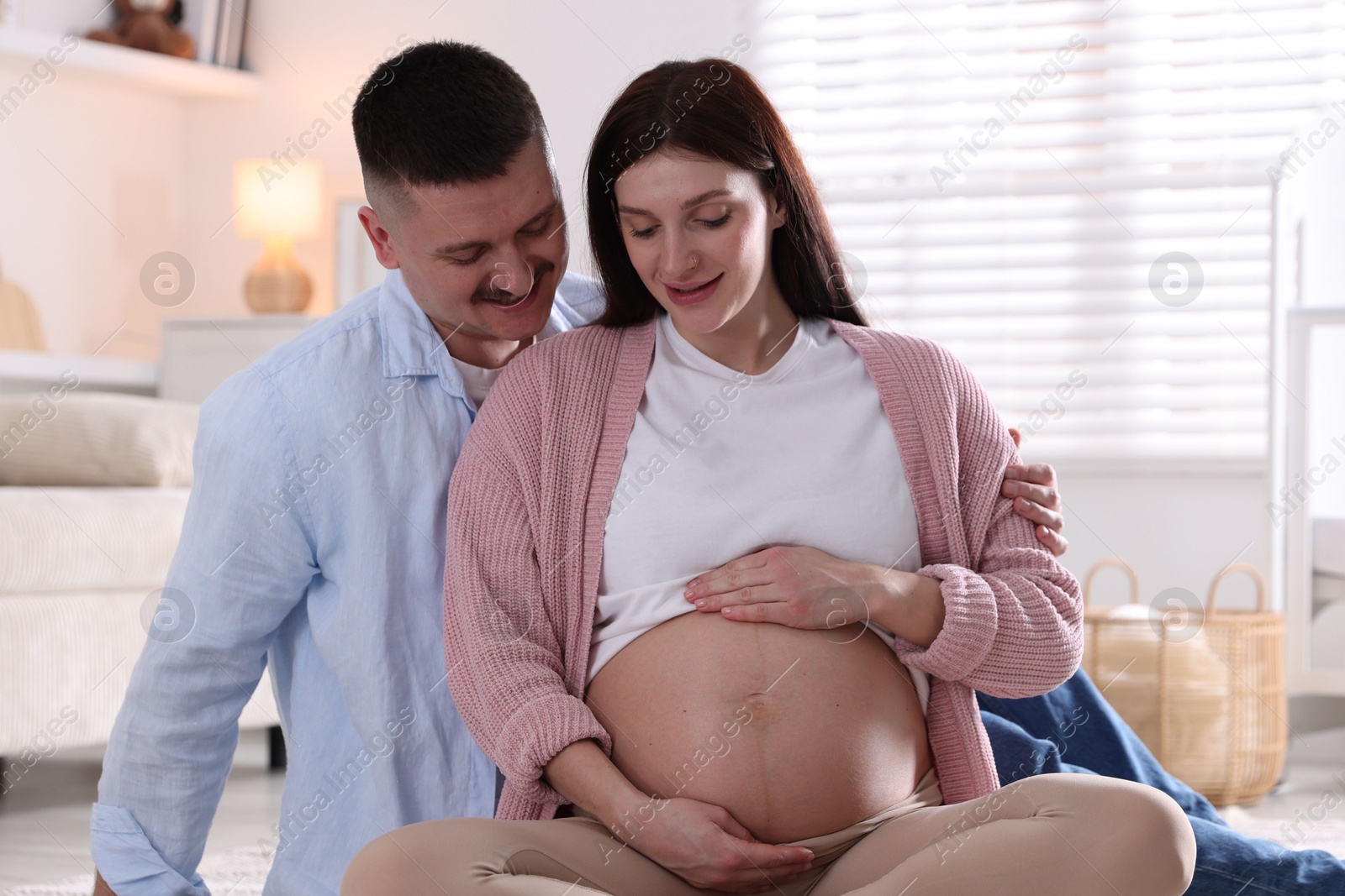 Photo of Pregnant woman and her husband on floor at home