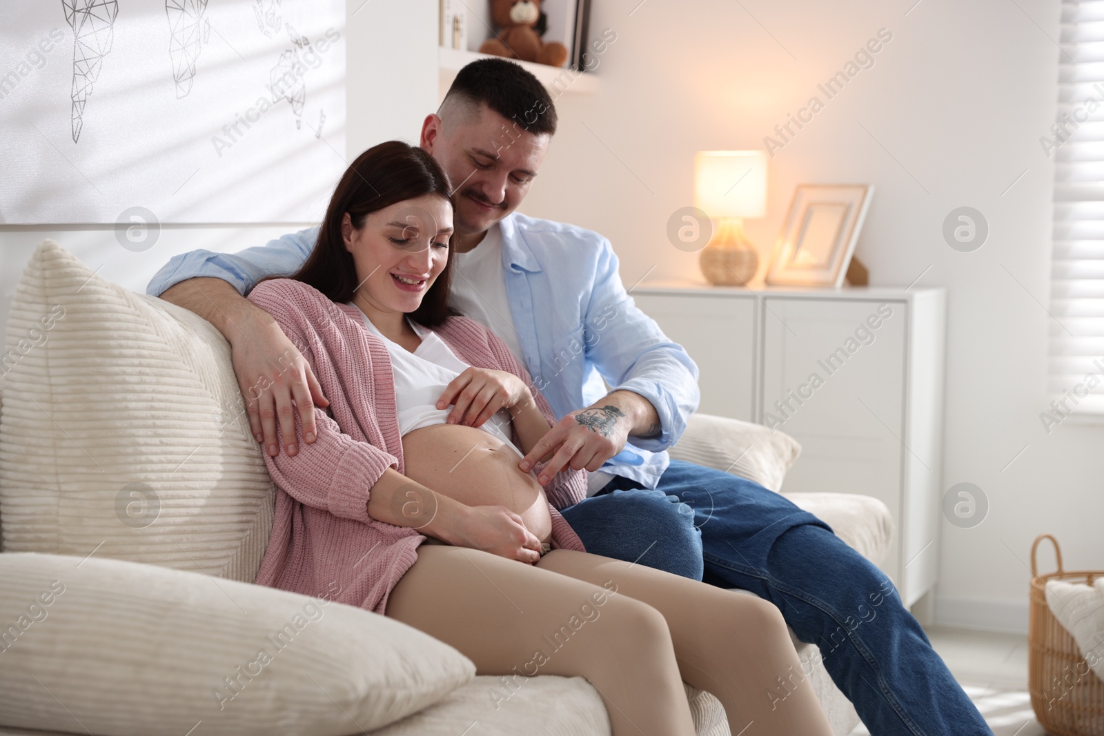 Photo of Pregnant woman and her husband on sofa at home