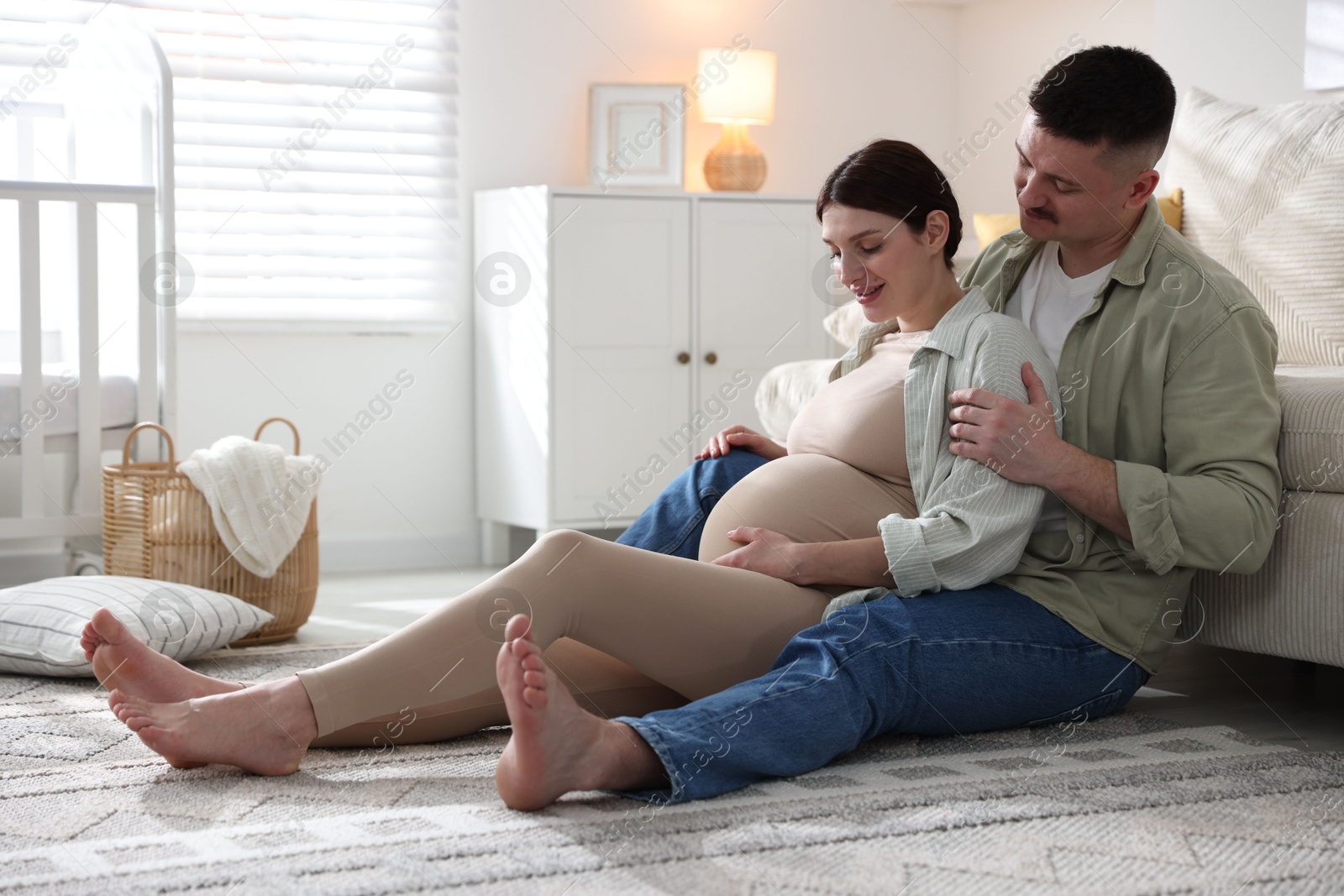 Photo of Pregnant woman and her husband on floor at home