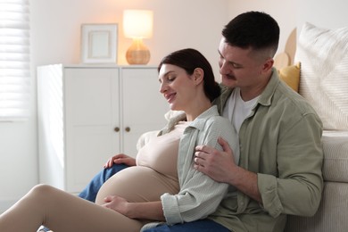 Photo of Pregnant woman and her husband on floor at home