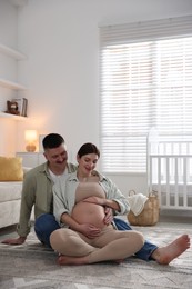 Photo of Pregnant woman and her husband on floor at home