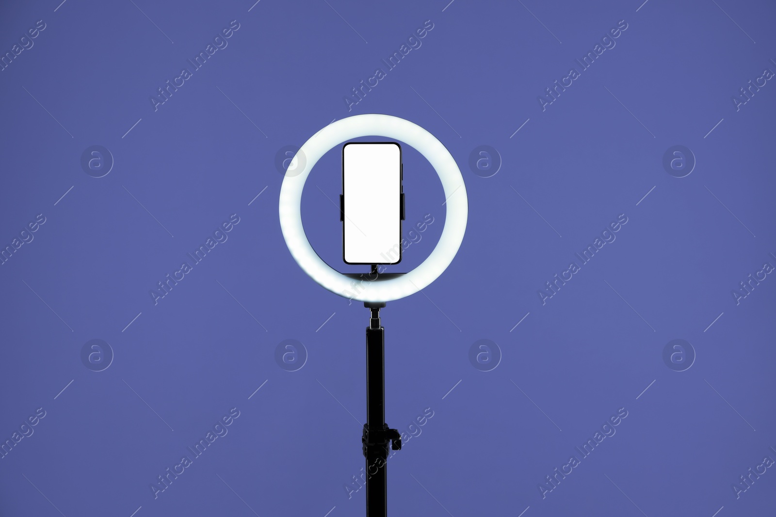 Photo of Ring lamp with smartphone on purple background