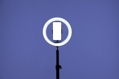 Photo of Ring lamp with smartphone on purple background