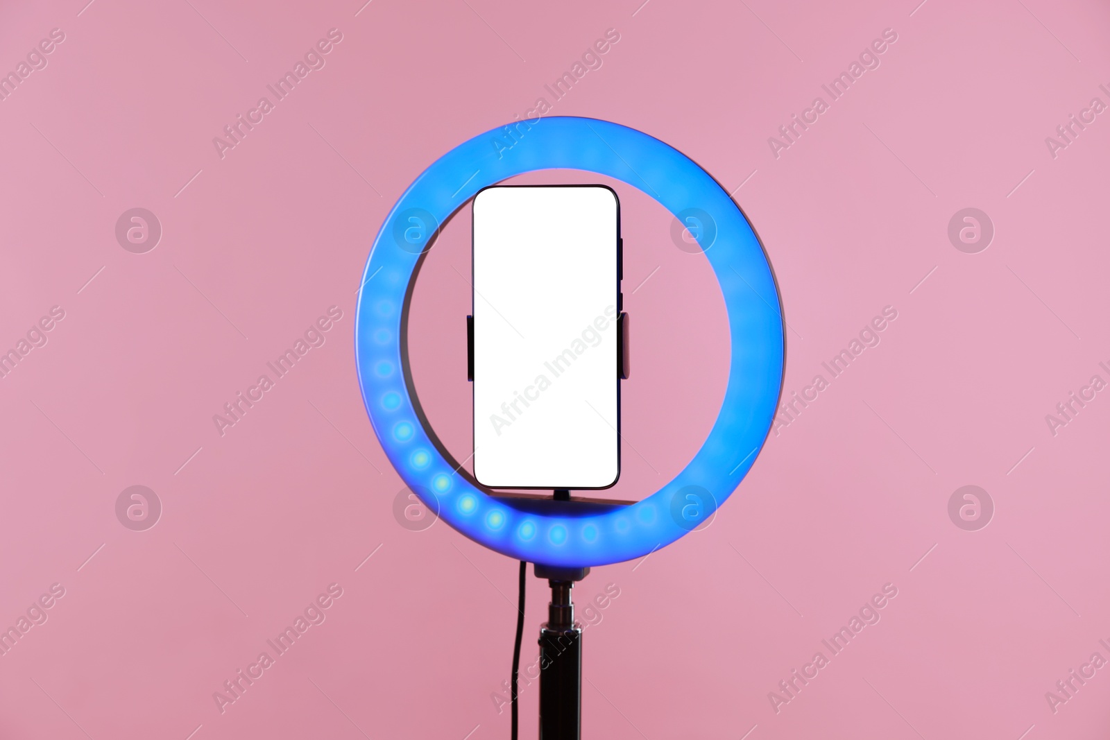 Photo of Ring lamp with smartphone on pink background