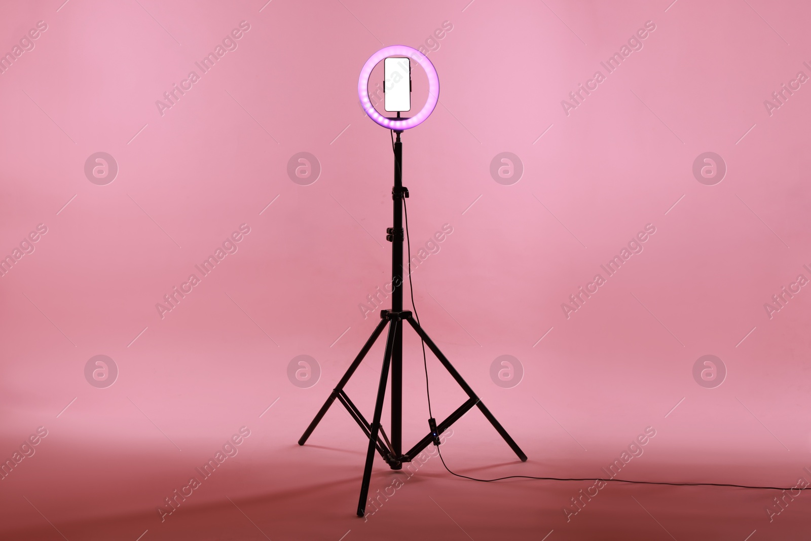 Photo of Ring lamp with smartphone on pink background