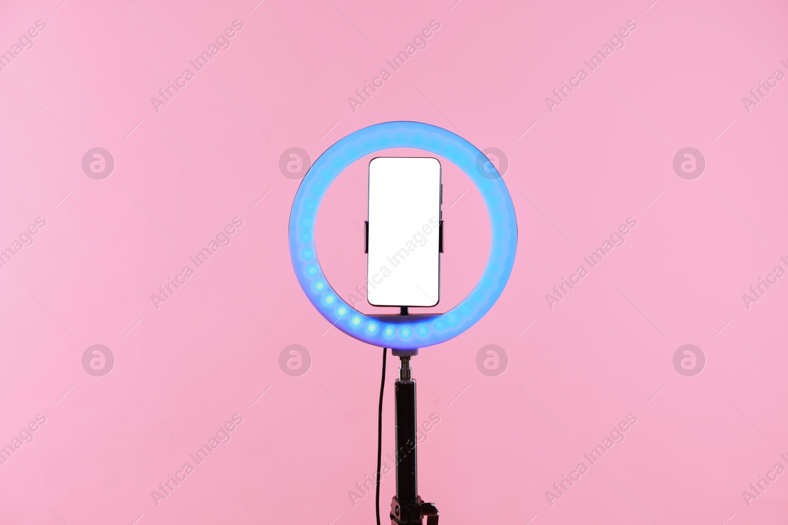 Photo of Ring lamp with smartphone on pink background