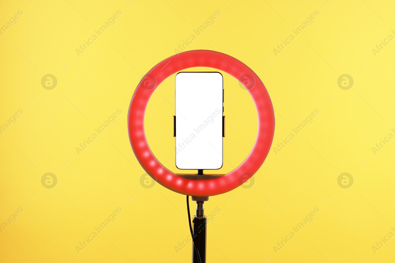 Photo of Ring lamp with smartphone on orange background