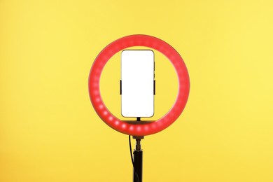 Photo of Ring lamp with smartphone on orange background