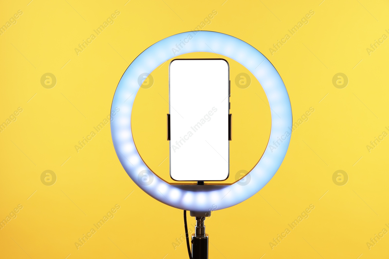 Photo of Ring lamp with smartphone on orange background