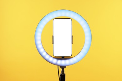 Photo of Ring lamp with smartphone on orange background