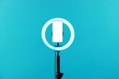 Photo of Ring lamp with smartphone on light blue background