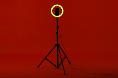 Photo of Ring lamp with smartphone on red background