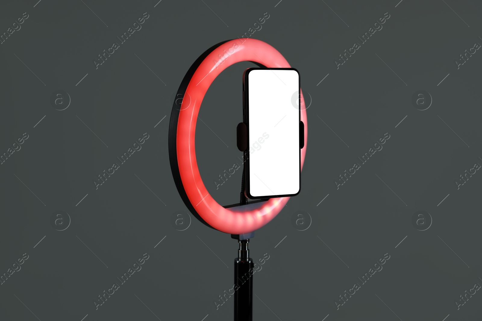 Photo of Ring lamp with smartphone on grey background