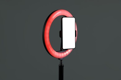 Photo of Ring lamp with smartphone on grey background