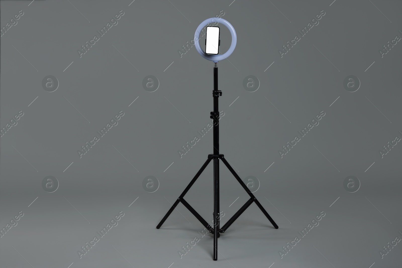 Photo of Ring lamp with smartphone on grey background