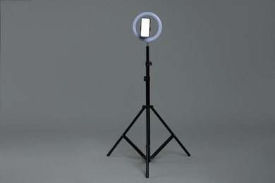 Photo of Ring lamp with smartphone on grey background