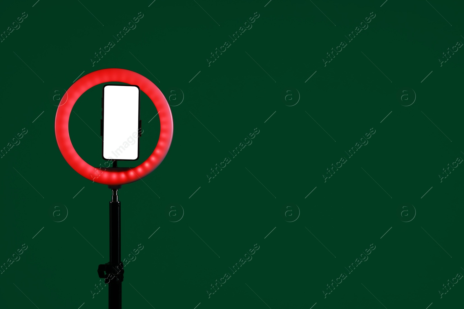 Photo of Ring lamp with smartphone on green background, space for text