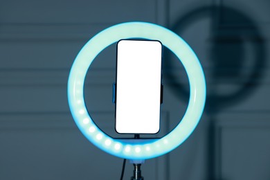 Photo of Ring lamp with smartphone against wall indoors