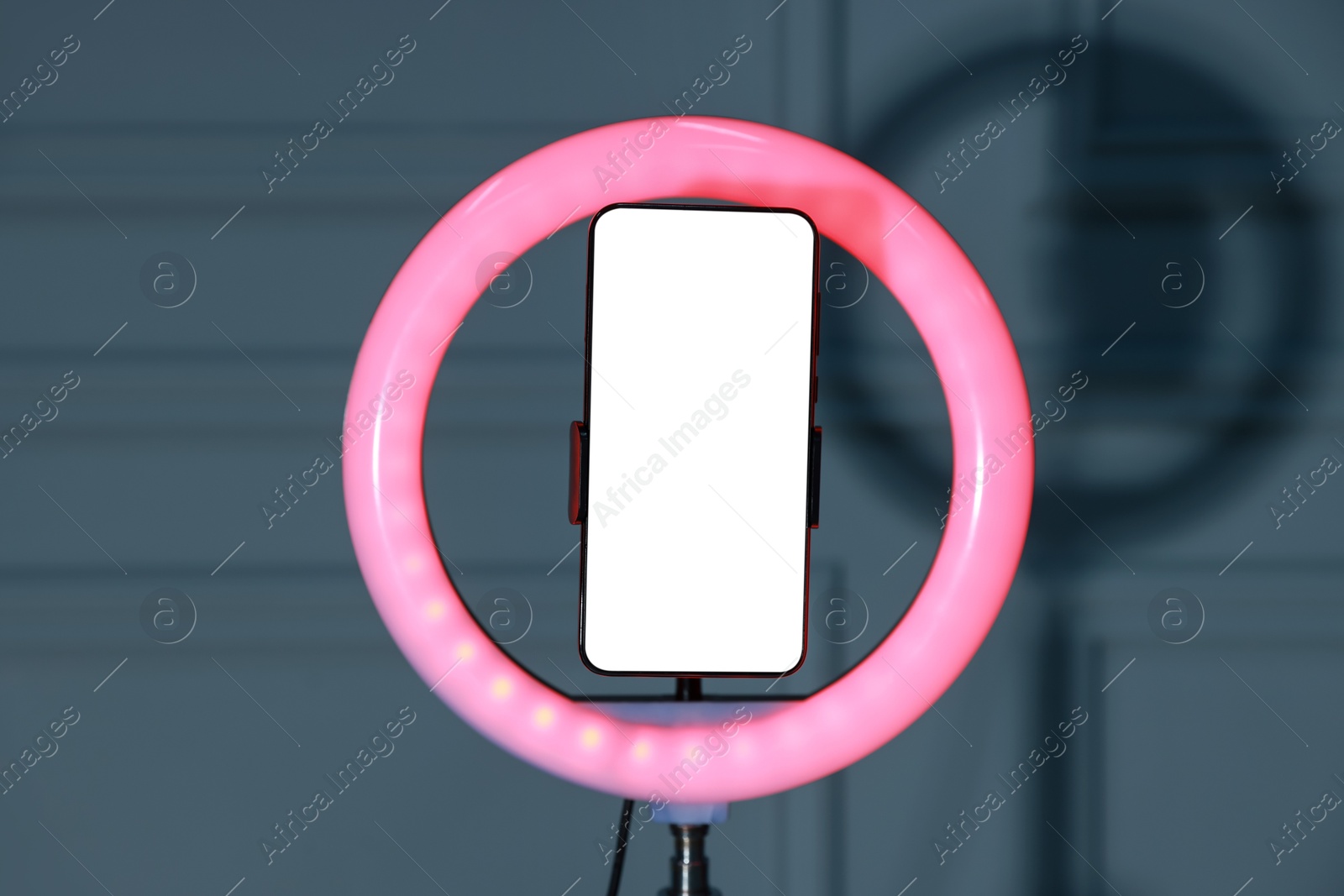 Photo of Ring lamp with smartphone against wall indoors