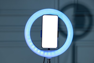 Photo of Ring lamp with smartphone against wall indoors